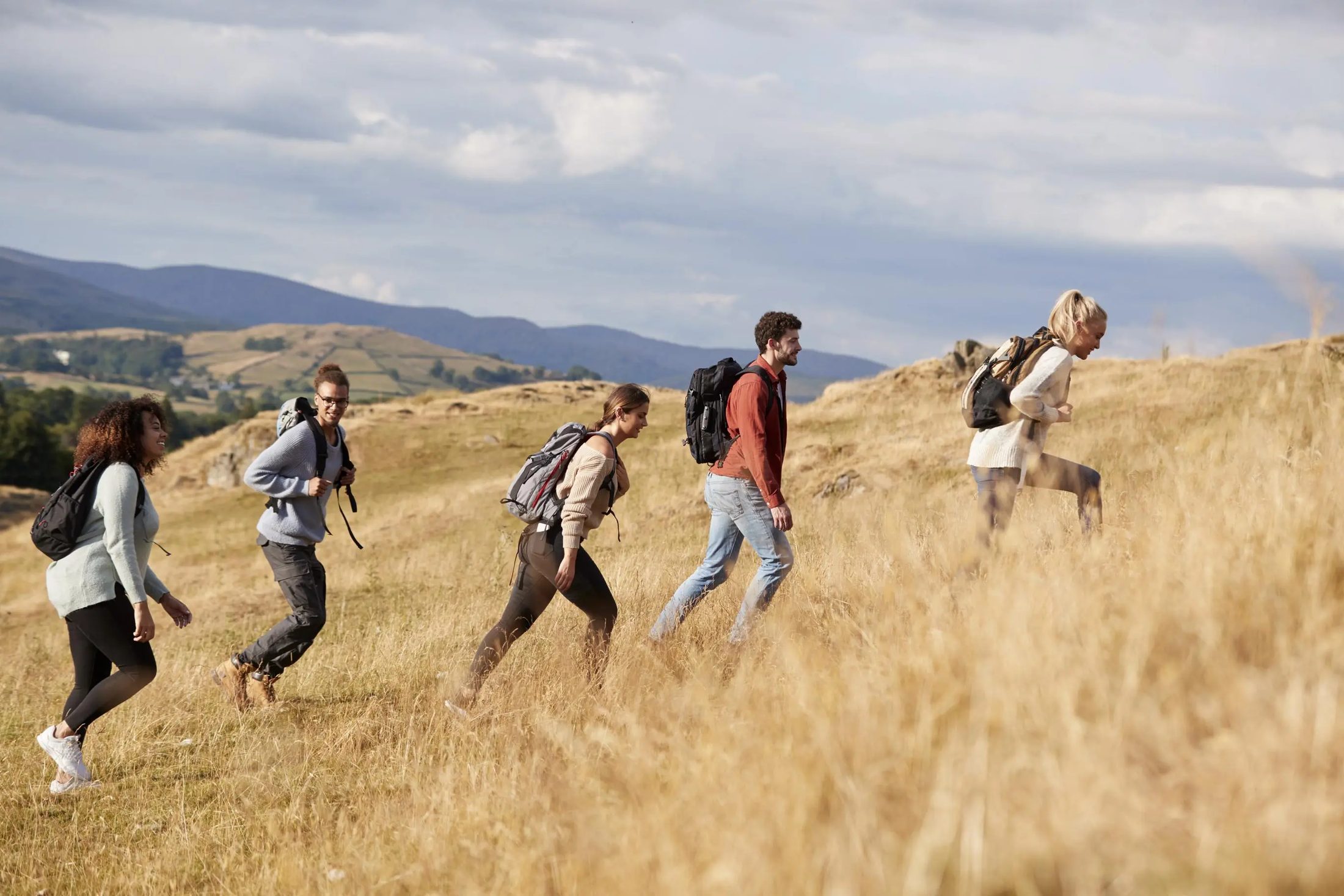 Friends hiking up a golden hillside trail