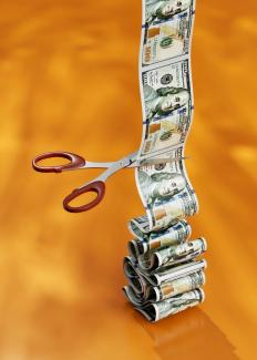 a stack of money sitting next to a pair of scissors by Igor Omilaev courtesy of Unsplash.