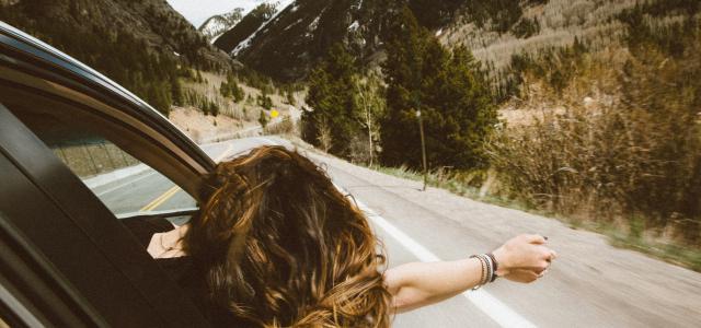 woman riding on vehicle putting her head and right arm outside the window while travelling the road by averie woodard courtesy of Unsplash.